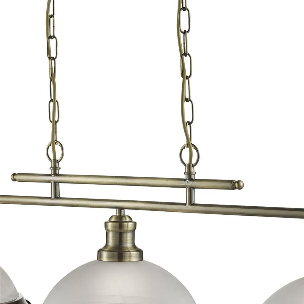 Lampa wisząca Bistro 3-punktowa w kolorze antycznego mosiądzu. Posiada trzy oprawy z białymi, szklanymi kloszami zawieszonymi na cienkich łańcuchach. Kąt ujęcia zbliżony, ukazujący detale konstrukcji i wykończenia.
