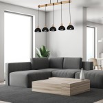 Lampa wisząca Erik 5-punktowa z czarnymi kloszami i naturalnym drewnianym uchwytem, zawieszona nad szarym narożnikiem w nowoczesnym wnętrzu. Jasne tło z oknem oraz zielona roślina dodają aranżacji świeżości.