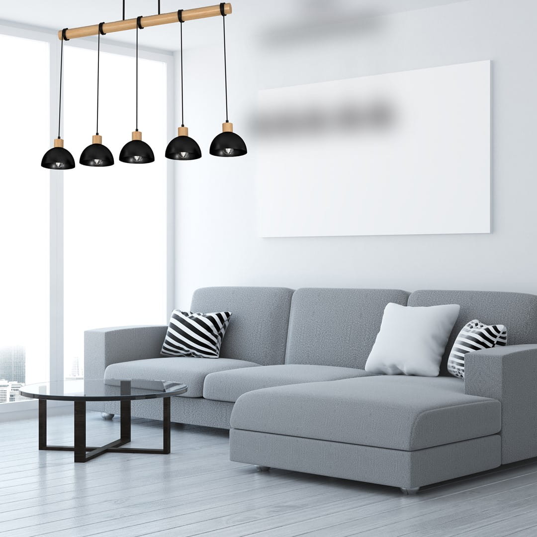 Lampa wisząca Erik 5-punktowa w kolorze czarnym z naturalnym drewnianym stelażem. Posiada pięć zaokrąglonych kloszy zawieszonych na czarnych przewodach, umieszczona nad nowoczesną szaro-skalową sofą w jasnym wnętrzu.