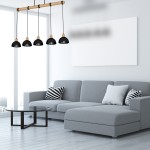Lampa wisząca Erik 5-punktowa w kolorze czarnym z naturalnym drewnianym stelażem. Posiada pięć zaokrąglonych kloszy zawieszonych na czarnych przewodach, umieszczona nad nowoczesną szaro-skalową sofą w jasnym wnętrzu.