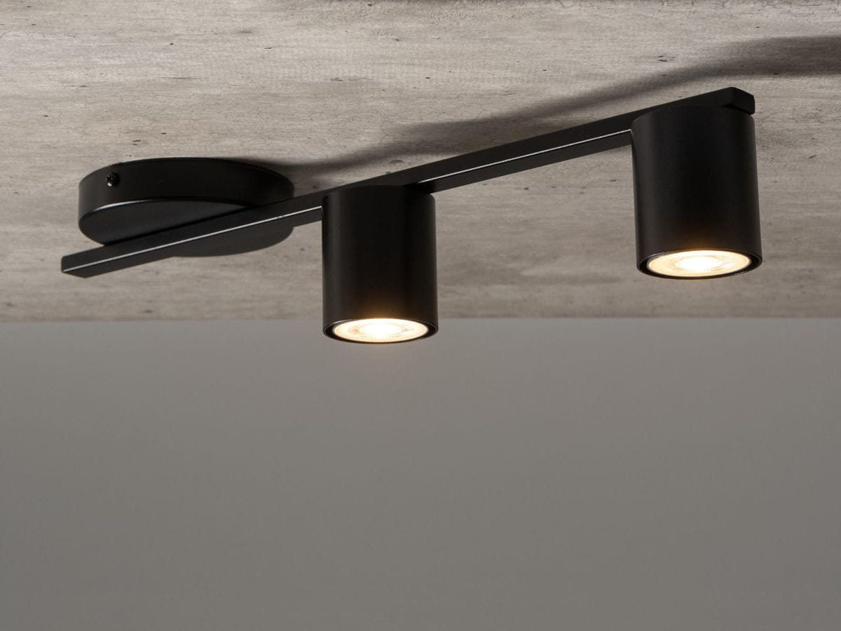 Lampa sufitowa Sky 2-punktowa w kolorze czarnym, zamontowana na stropie, z dwoma cylindrycznymi kloszami emitującymi światło. Ujęcie z dołu, ukazujące nowoczesny design i prostą formę.