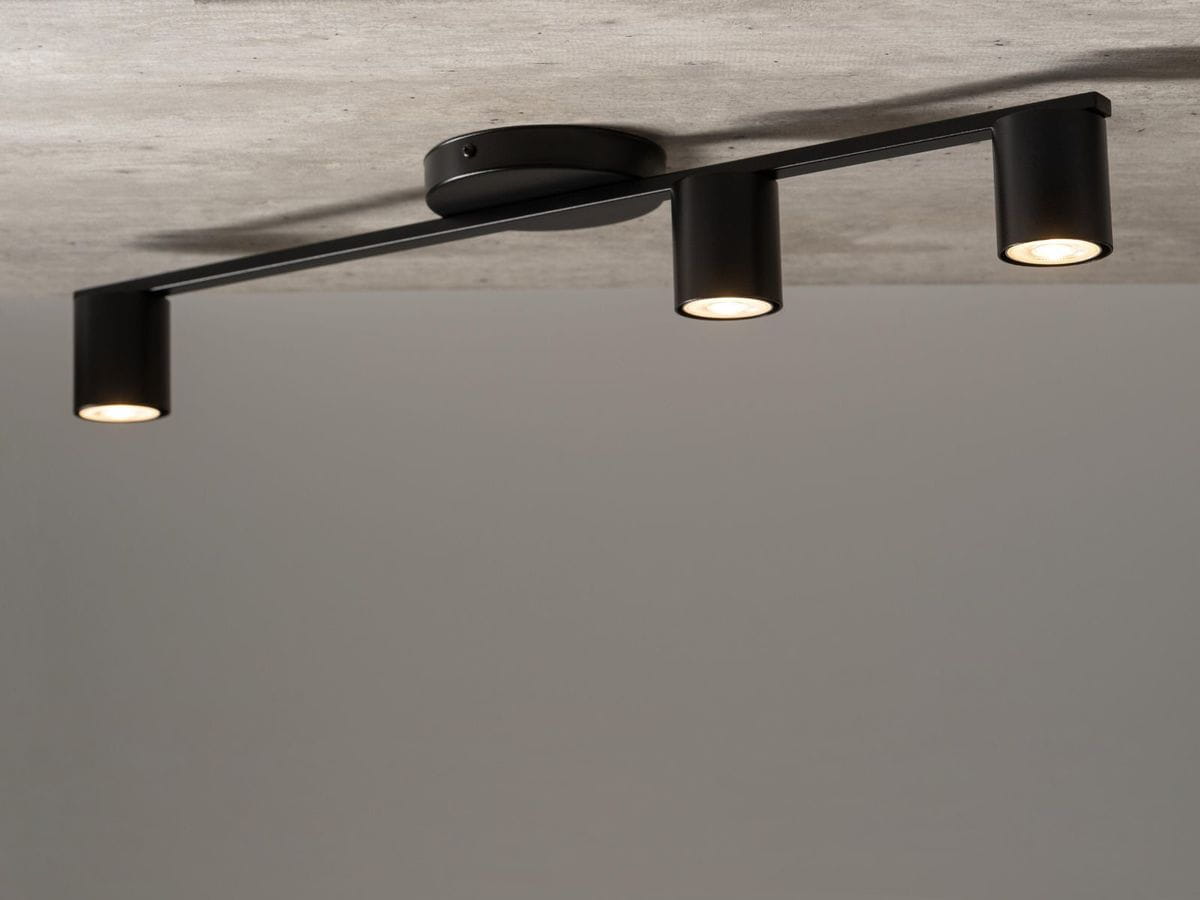 Czarna lampa sufitowa 3-punktowa Sky z metalowymi kloszami, umieszczona na prostokątnej podstawie. Ujęcie z dołu, z widocznymi trzema punktami świetlnymi, które skierowane są w dół. Prosty, nowoczesny design pasujący do różnych wnętrz.