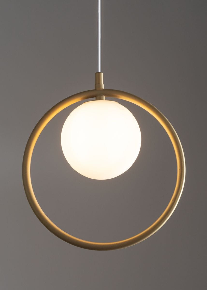 Wisząca lampa Aqua 1-punktowa w kolorze złotym z okrągłą metalową oprawą. W centralnej części znajduje się biały, matowy klosz w kształcie kuli. Lampa zawieszona na przezroczystym przewodzie, prezentująca nowoczesny design.