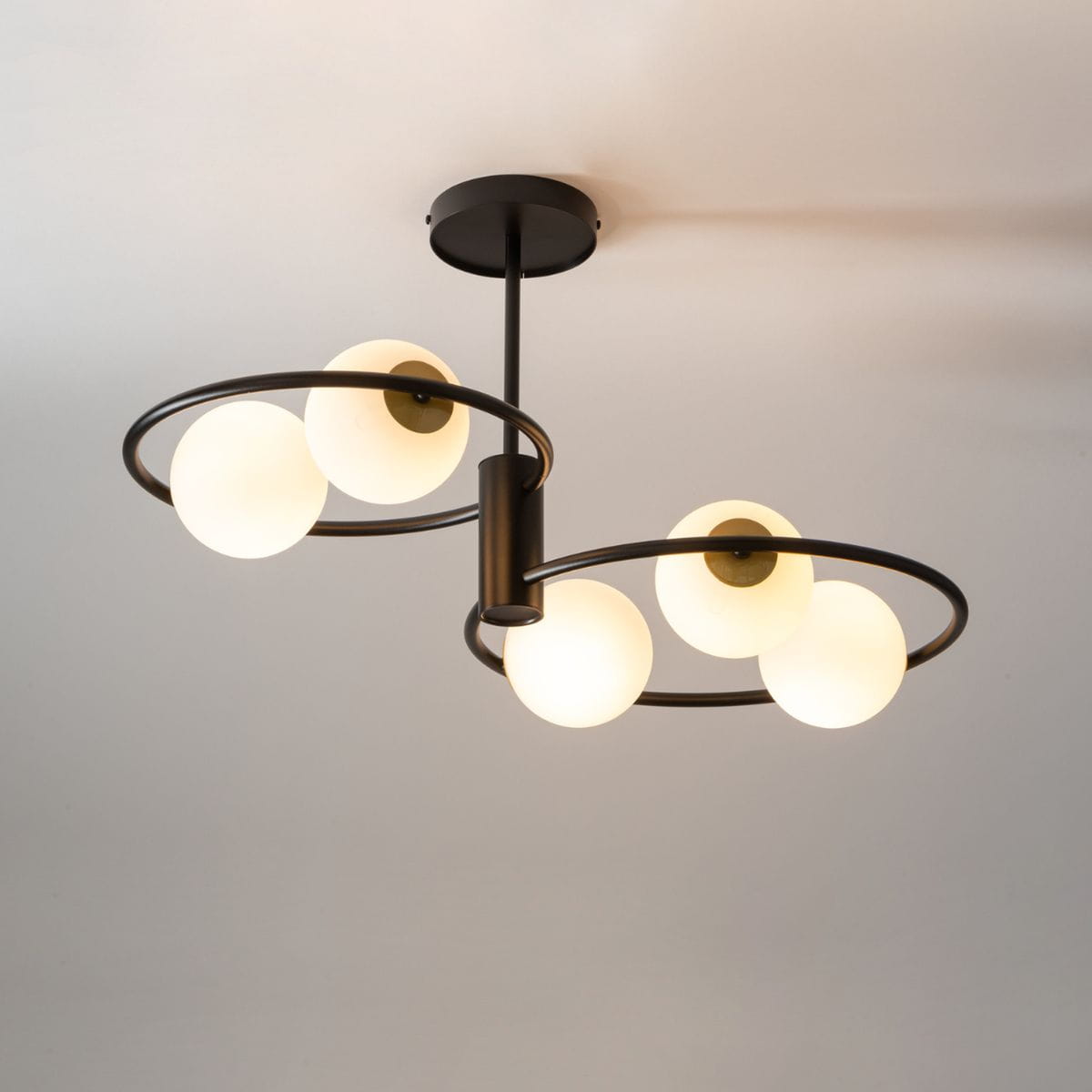 Lampa wisząca Aqua 5-punktowa w kolorze czarnym i złotym. Konstrukcja z metalowymi okręgami i pięcioma okrągłymi, matowymi kloszami w białym kolorze. Ujęcie z dołu, ukazujące detale zawieszenia i rozmieszczenie kloszy.