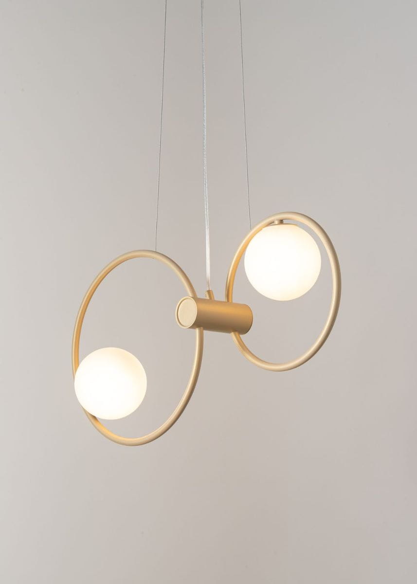 Lampa wisząca Aqua 2-punktowa w złotym kolorze, z dwiema białymi, okrągłymi kulami na minimalistycznych okręgach. Produkt zawieszony na cienkim, przezroczystym przewodzie, na jasnym tle.