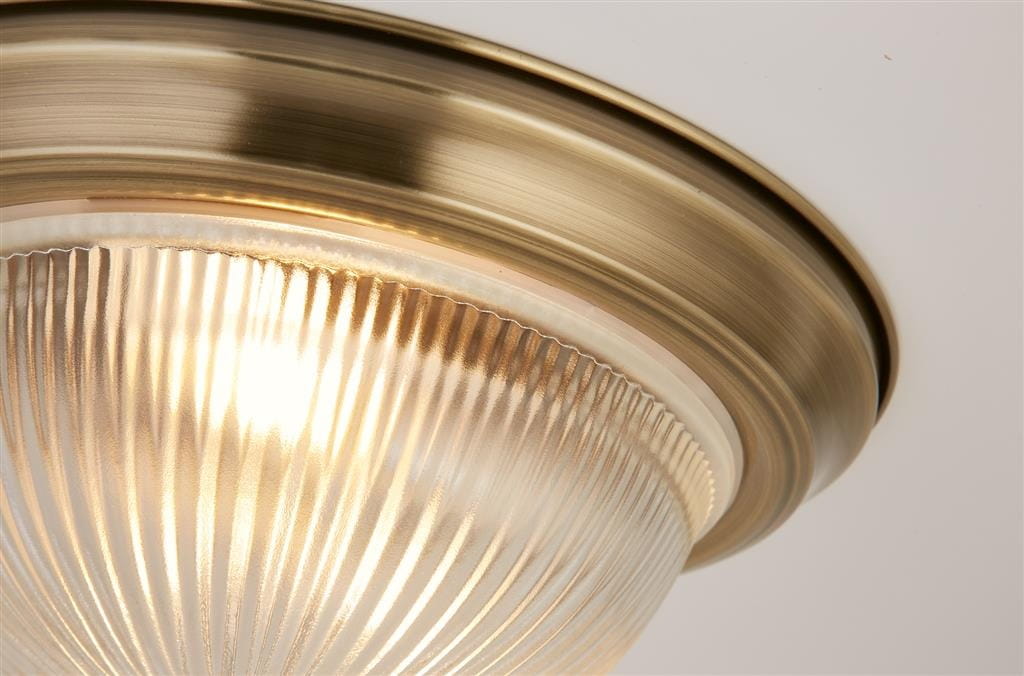 Lampa sufitowa American Diner IP44, 2-punktowa, w antycznym mosiądzu. Szklany klosz z wyraźnym prążkowaniem, emitujący ciepłe światło. Ujęcie z góry, pokazujące detale wykończenia oraz montaż na suficie.