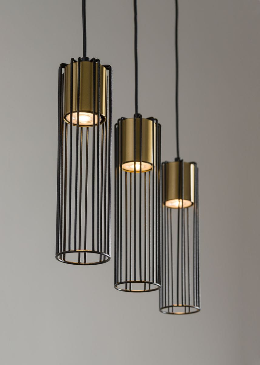 Lampa wisząca Fobia 3-punktowa w kolorze czarnym i złotym. Składa się z trzech cylindrycznych kloszy z metalowymi, szczelinowymi osłonami. Produkt zawieszony na czarnych przewodach, w eleganckim, nowoczesnym stylu, idealny do wnętrz.