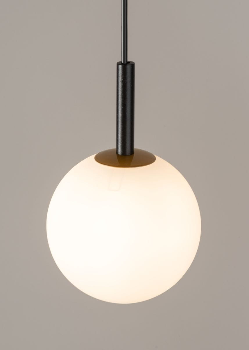 Czarna lampa wisząca Gama 1-punktowa z okrągłym, matowym kloszem w kolorze białym. Produkt zawieszony na cienkim, czarnym przewodzie. Klosz ma gładką powierzchnię i jest umieszczony na złotej podstawie. Idealna do nowoczesnych wnętrz.