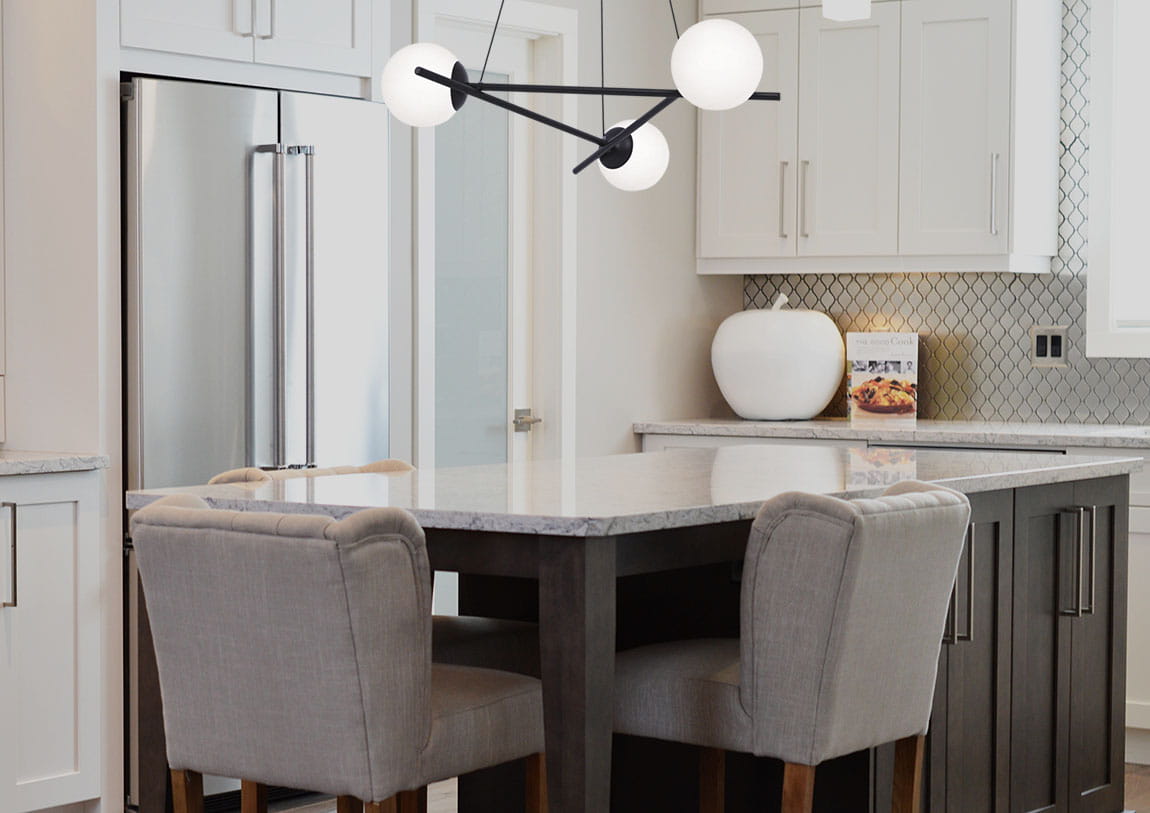 Lampa wisząca Arton 3-punktowa w kolorze czarnym z trzema białymi kloszami, zawieszona nad kuchennym wyspą. Kąt ujęcia z boku, ukazujący nowoczesny design i minimalistyczny styl. Tło jasne, kuchenne z elementami w odcieniach szarości i bieli.