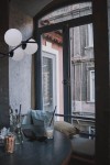 Lampa wisząca Arton 6-punktowa w czarnym kolorze z okrągłymi, matowymi kloszami, zawieszona w pobliżu okna. W tle widoczny stół z szklanką i okularami przeciwsłonecznymi, w jasnym, nowoczesnym wnętrzu.