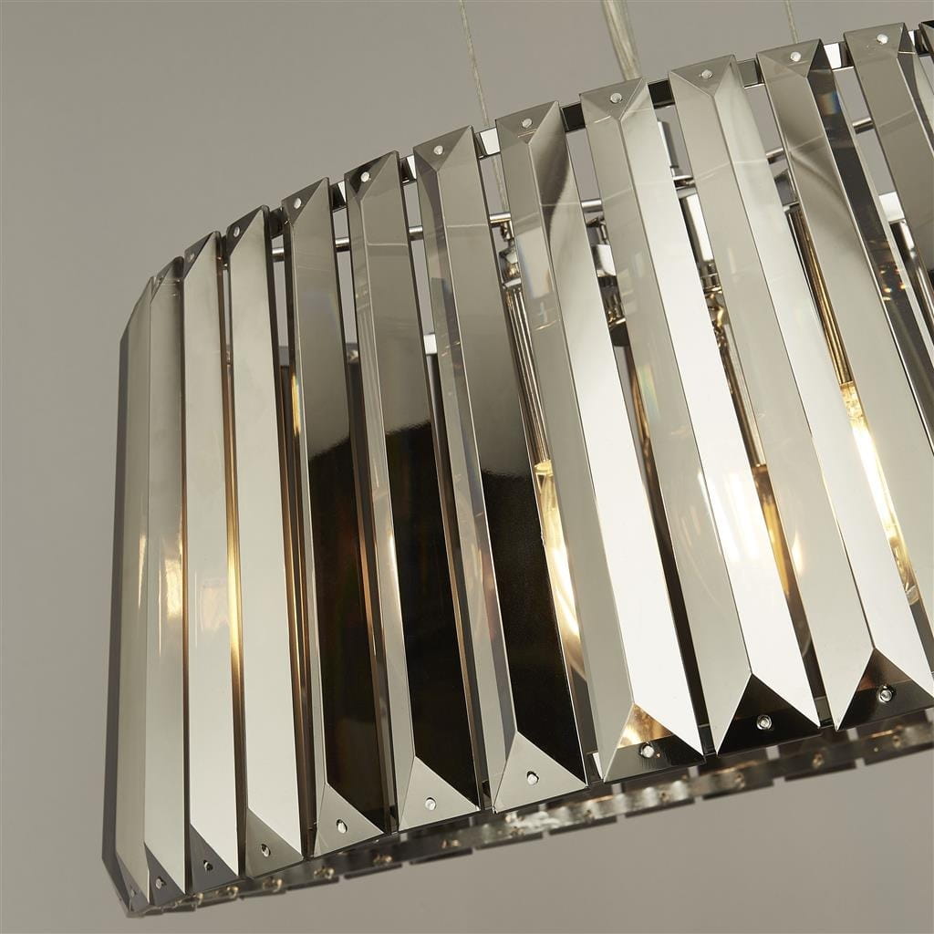 Tiara lampa wisząca 5-punktowa w kolorze chromu z przydymionymi detalami. Okrągła forma z wieloma pionowymi, lustrzanymi elementami, zawieszona na cienkich linkach. Widoczna od góry, z eleganckimi krawędziami i subtelnym blaskiem.