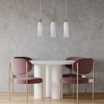 Lampa wisząca Piega 3-punktowa w kolorze patyny i białym, z trzema szklanymi kloszami w kształcie dzwonu. Zawieszona nad okrągłym białym stołem, w otoczeniu różowych krzeseł z metalowymi nogami, na tle szarej ściany.