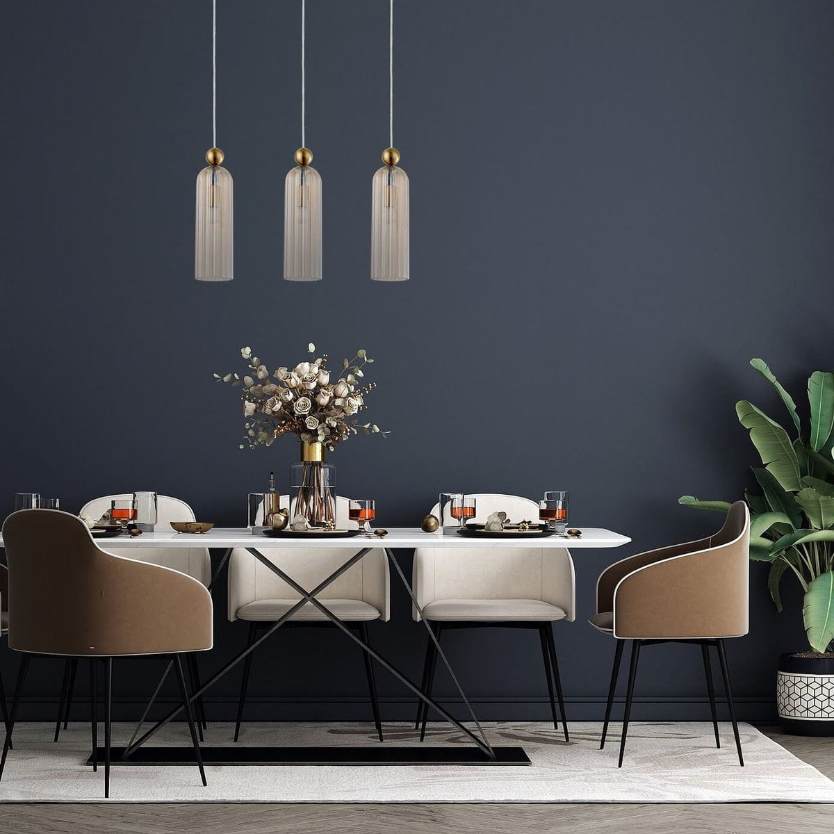 Lampa wisząca Piega 3-punktowa w kolorze patyna z dymionym kloszem. Zawieszona na białych linkach, znajduje się nad nowoczesnym stołem w jadalni, otoczona eleganckimi krzesłami i dekoracją w wazonie. Tło w ciemnym odcieniu.