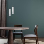Lampa wisząca Manacor LP-232/1P WH w kolorze białym, cylindryczna, zawieszona na cienkim sznurku, umieszczona nad okrągłym drewnianym stołem w minimalistycznym wnętrzu. W tle widoczne ciemnozielone ściany i zasłony.