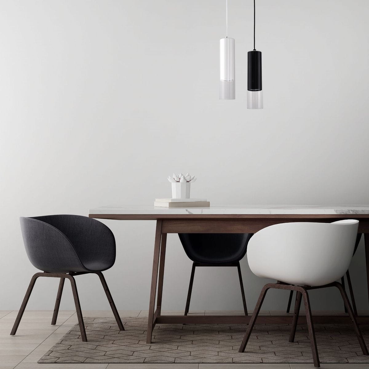 Lampa wisząca Manacor LP-232/1P WH w białym kolorze, cylindryczny kształt, zawieszona nad stołem. W tle widać drewniany stół oraz krzesła w odcieniach szarości i bieli. Na stole dekoracyjna kompozycja z kwiatów. Tło jasnoszare, minimalistyczne.