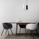 Lampa wisząca Manacor LP-232/1P WH w białym kolorze, cylindryczny kształt, zawieszona nad stołem. W tle widać drewniany stół oraz krzesła w odcieniach szarości i bieli. Na stole dekoracyjna kompozycja z kwiatów. Tło jasnoszare, minimalistyczne.
