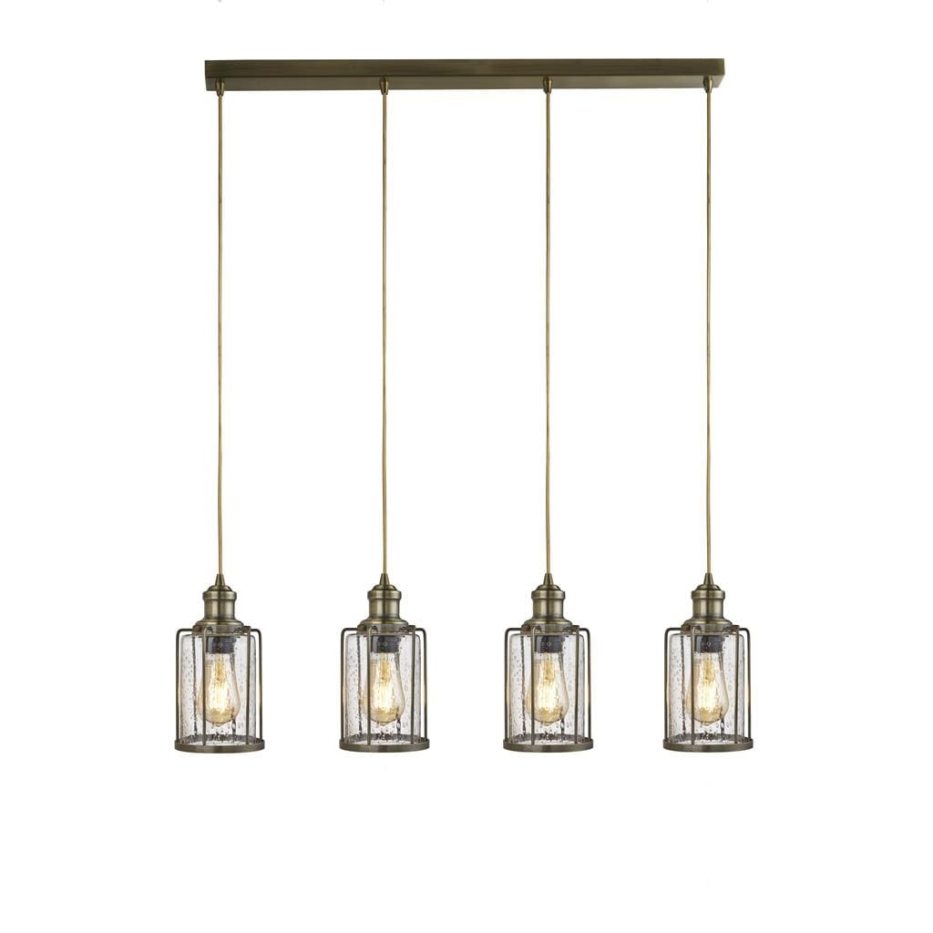 Lampa wisząca 4-punktowa Pipes w antycznym mosiądzu, z czterema kloszami w kształcie cylindrów z przezroczystego szkła, zawieszona na prostokątnej podstawie. Klosze mają metalowe ramki, a każdy z nich zawiera żarówkę.