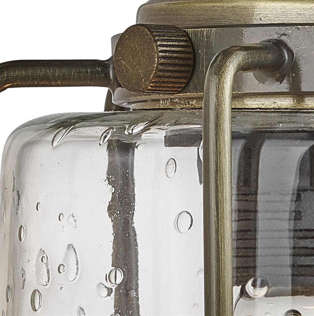 Kinkiet Pipes 1-punktowy w antycznym mosiądzu, z przezroczystym kloszem z teksturowanego szkła. Widoczny detal metalowego mocowania oraz ozdobny pokrętło. Klosz ma okrągły kształt, a na powierzchni widoczne są drobne krople wody.