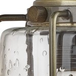 Kinkiet Pipes 1-punktowy w antycznym mosiądzu, z przezroczystym kloszem z teksturowanego szkła. Widoczny detal metalowego mocowania oraz ozdobny pokrętło. Klosz ma okrągły kształt, a na powierzchni widoczne są drobne krople wody.