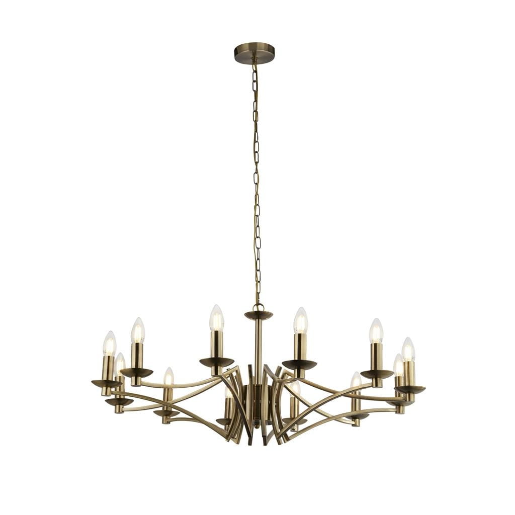 Lampa wisząca Ascot 12-punktowa w antycznym mosiądzu. Posiada 12 ramion z lampami w kształcie świec. Kształt lekko falisty, zawieszona na łańcuchu. Idealna do stylowych wnętrz. Tło białe, co podkreśla elegancję lampy.