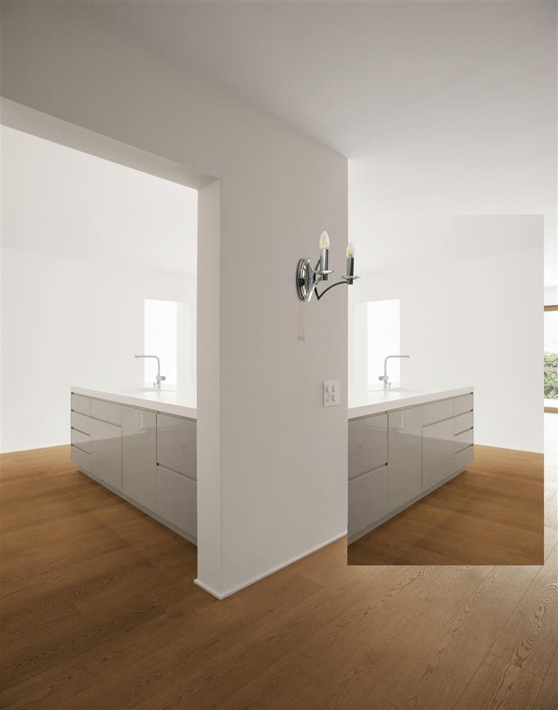 Kinkiet Ascot 2-punktowy w kolorze chromowanym, zamontowany na ścianie w kuchni. Posiada dwa żarówki w kształcie świec. Tło jasne, minimalistyczne, z widocznymi meblami kuchennymi w odcieniu szaro-srebrnym oraz drewnianą podłogą.