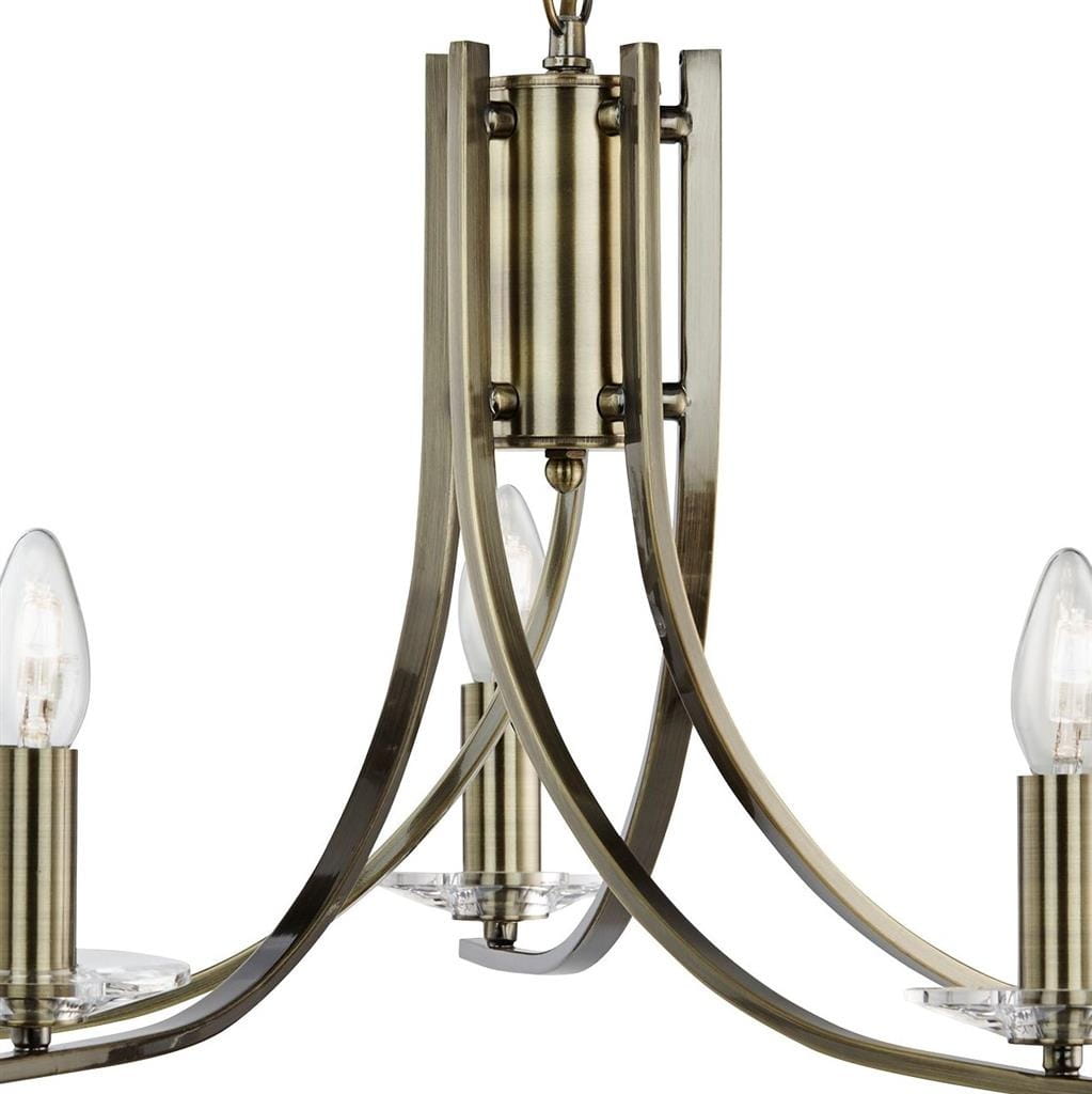 Lampa wisząca Ascona w kolorze antycznego mosiądzu z pięcioma punktami świetlnymi. Posiada zaokrąglone ramiona i elegancki, minimalistyczny design. Widoczne przezroczyste klosze na żarówki, metalowa konstrukcja. Ujęcie z boku, zbliżenie na detal.
