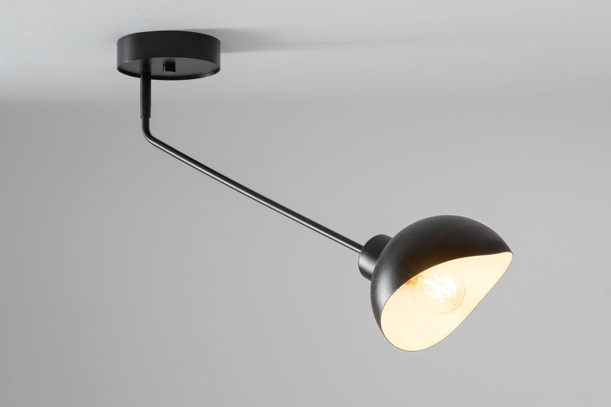 Czarna lampa sufitowa Roy z białym kloszem, z metalowym uchwytem. Ujęcie z boku, lampa zamontowana na suficie, z lekko wygiętym ramieniem. Klosz w kształcie stożka, odsłania żarówkę, tło jasne, minimalistyczne.