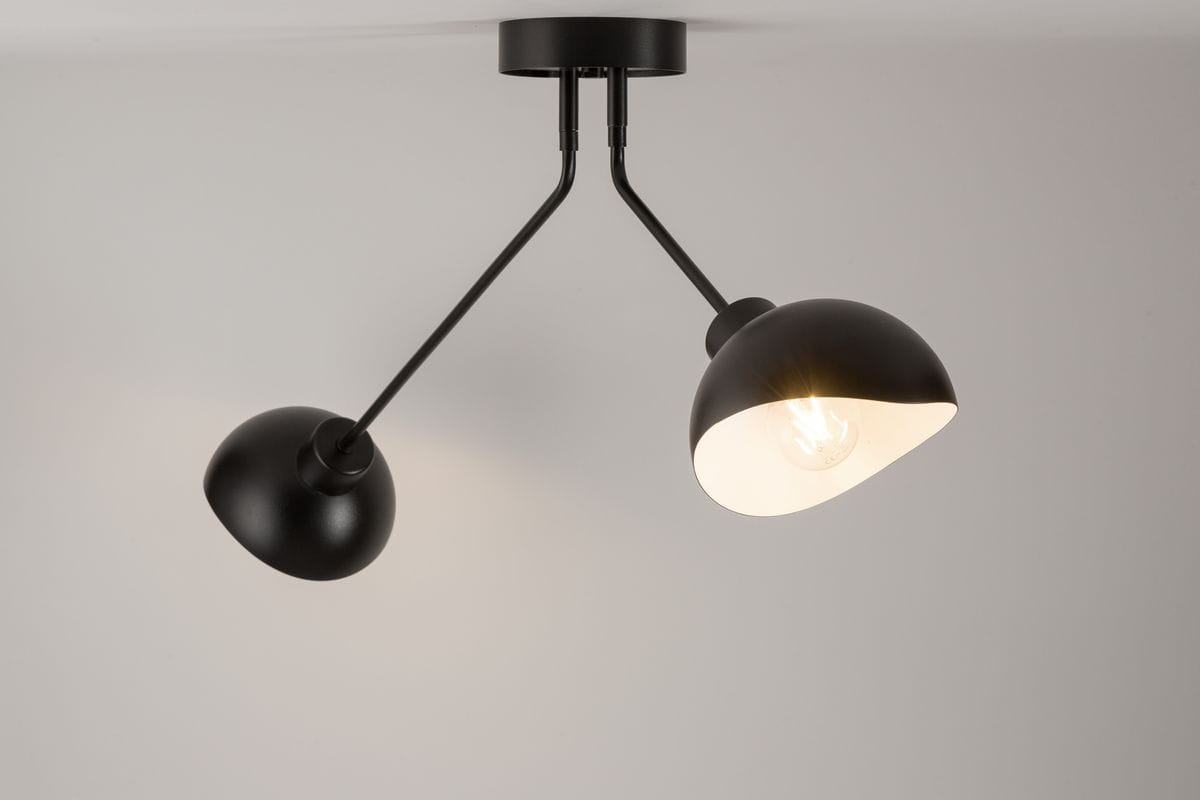 Lampa sufitowa Roy 2-punktowa w kolorze czarnym i białym. Posiada dwa klosze w kształcie półkuli, zamocowane na regulowanych ramionach. Ujęcie z dołu, ukazujące detal wykończenia i źródła światła.
