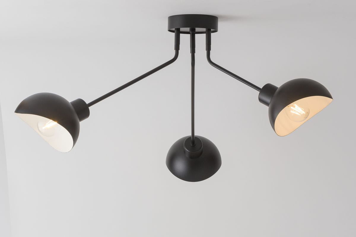 Czarna lampa sufitowa 3-punktowa Roy z białymi kloszami, zawieszona na trzech cienkich ramionach. Klosze o półkulistym kształcie, centralny uchwyt w formie czarnej, matowej czaszy. Produkt montowany na suficie, w minimalistycznym stylu.