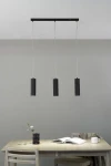 Lampa wisząca Costilla 3-punktowa w kolorze grafitowym. Składa się z trzech cylindrycznych kloszy z rowkowaną fakturą, zawieszonych na cienkich linkach. Montaż sufitowy, umiejscowiona nad drewnianym stołem. Tło w odcieniu szarym.