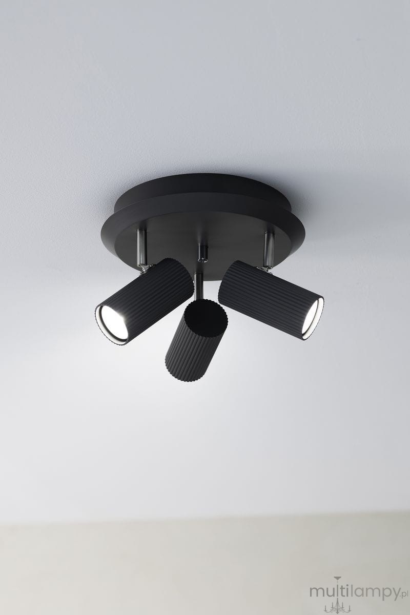 Lampa sufitowa Costilla 3-punktowa w kolorze grafitowym, z trzema cylindrycznymi reflektorami o rowkowanej fakturze. Zamontowana na okrągłej podstawie, skierowana w dół, idealna do oświetlenia wnętrz. Tło jasne, minimalistyczne.