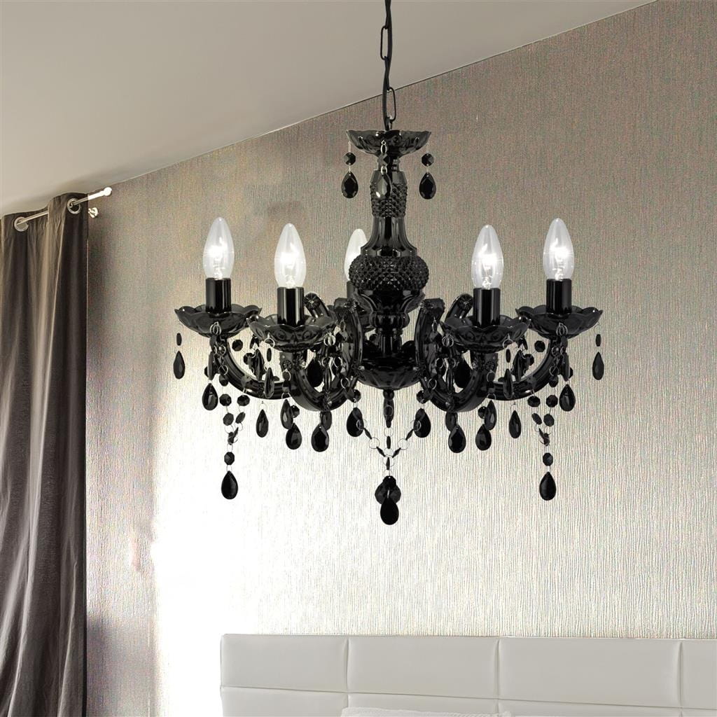 Czarny żyrandol Marie Therese 5-punktowy, z eleganckimi kloszami w kształcie świec i dekoracyjnymi kryształkami. Wisi na cienkim łańcuszku, idealny do stylowych wnętrz. Tło w odcieniu szaro-srebrnym, z zasłonami w kolorze szarym.