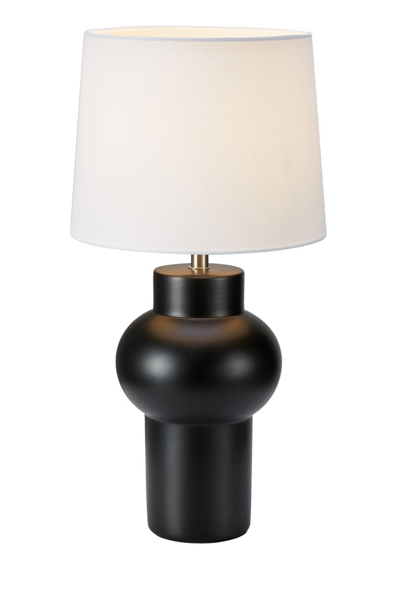 Lampa stołowa Shape w kolorze czarnym z białym abażurem. Okrągła podstawa z matowego metalu, zwężająca się ku dołowi. Abażur w kształcie cylindrycznym, lekko zaokrąglony u góry. Złoty detal przy mocowaniu abażuru. Ujęcie frontalne, stojąca.