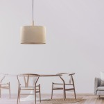 Lampa wisząca Deva Nature 1-punktowa 6107 o okrągłym, jasnobeżowym kloszu z tkaniny, zawieszona na czarnym przewodzie. W tle widoczna drewniana stół z krzesłami w skandynawskim stylu, na jasnym tle.