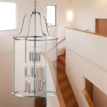 Lampa wisząca Lantern Grande 12-punktowa w chromie, z przezroczystym kloszem i elegancką konstrukcją. Zawieszona w przestrzeni, nad schodami, ukazuje nowoczesny design i estetykę. Widoczne źródła światła w formie świec.