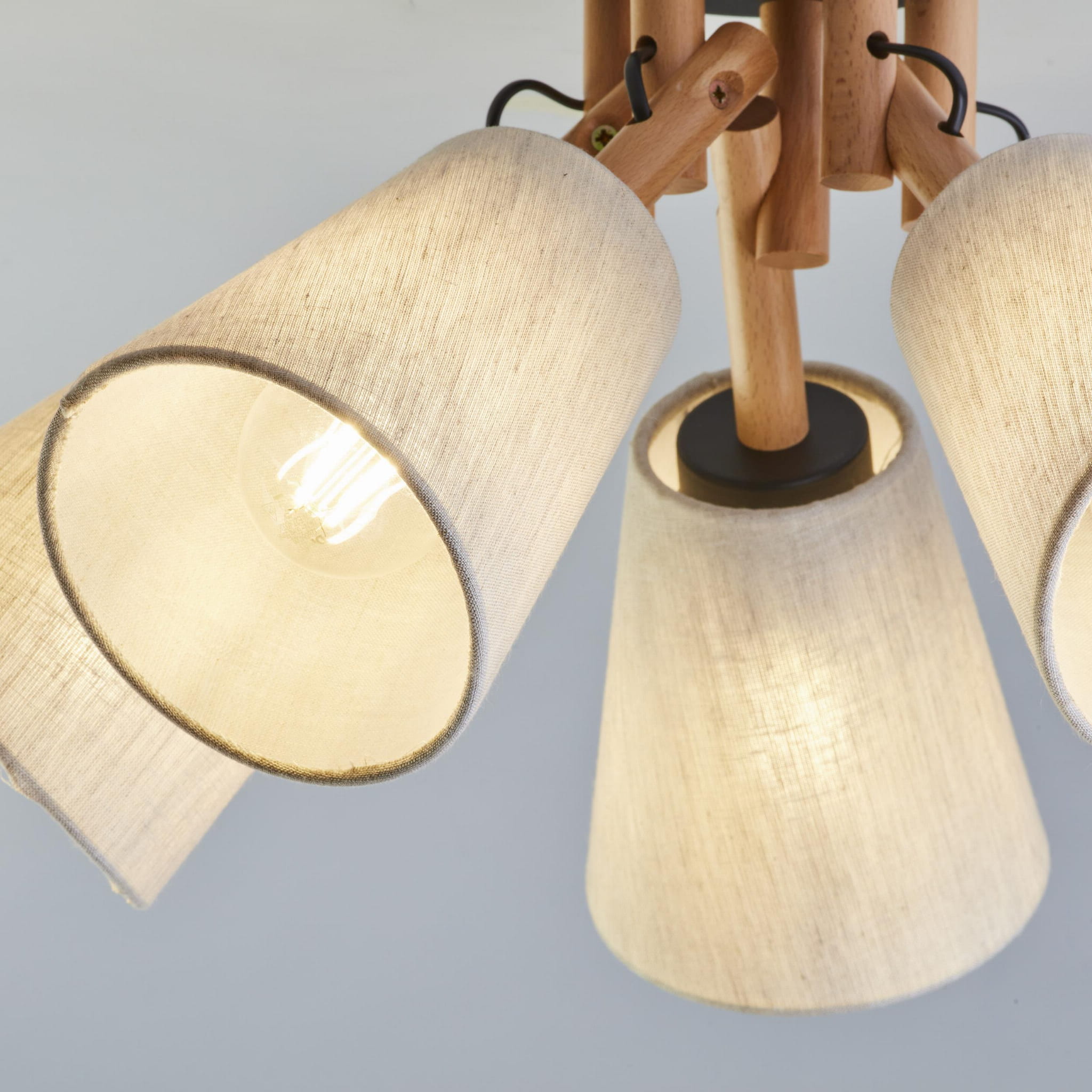 Vaio lampa sufitowa 5-punktowa w kolorze czarnym z tekstylnymi kloszami w odcieniu jasnego beżu. Lampa o drewnianej konstrukcji, z pięcioma kloszami skierowanymi w różnych kierunkach, zawieszona na centralnym mocowaniu.