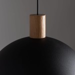Czarna lampa wisząca Oslo z 1 punktem świetlnym, o okrągłej, matowej czaszy i drewnianym detalem na górze. Lampa zawieszona na cienkim przewodzie, ukazująca minimalistyczny design i elegancki styl.