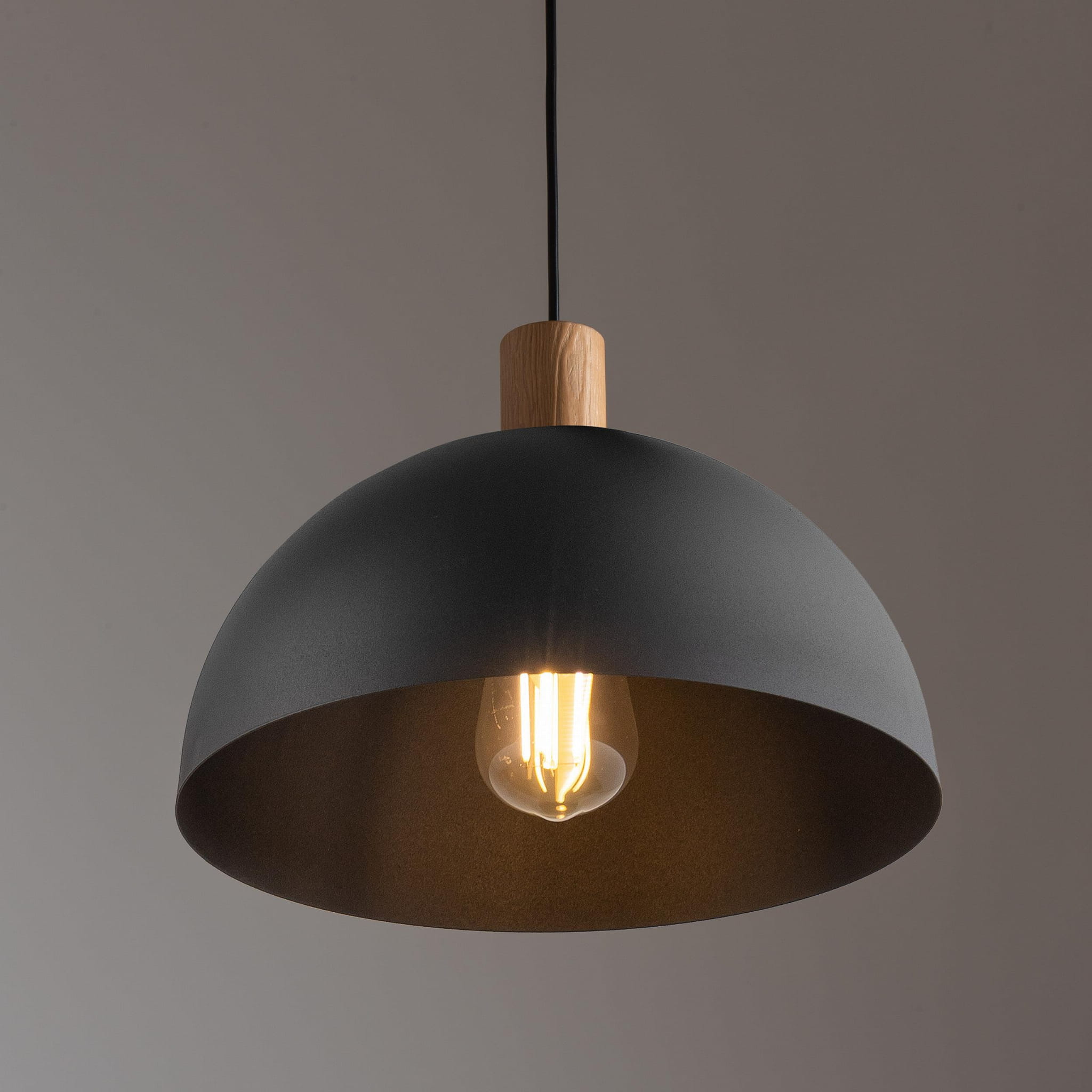 Czarna lampa wisząca Oslo z metalowym kloszem w kształcie półkuli i drewnianym uchwytem. Widoczna żarówka w środku, zawieszona na czarnym kablu. Prosta forma, idealna do nowoczesnych wnętrz.