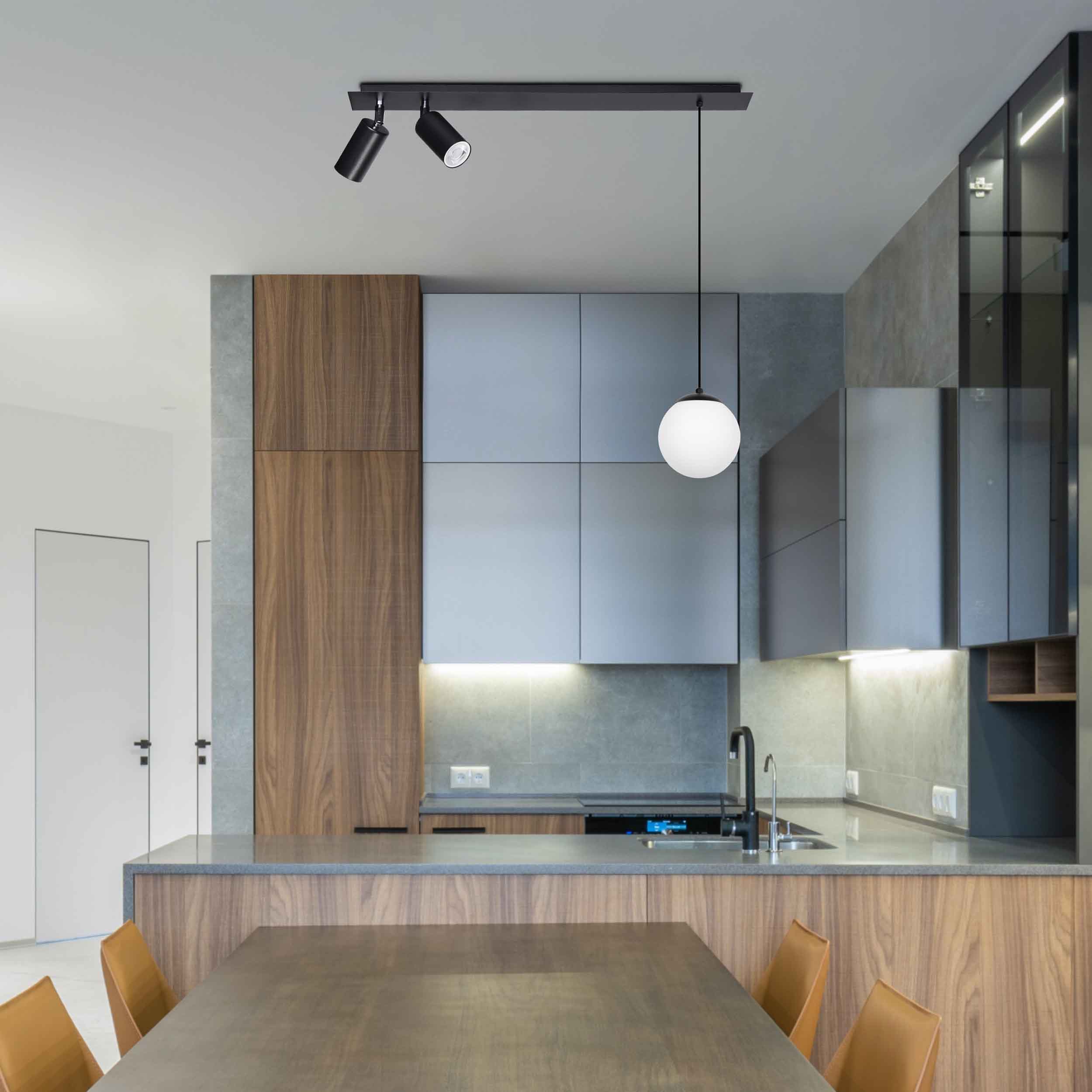 Albio lampa wisząca 3-punktowa, czarna, z dwoma reflektorami i jedną kulistą lampą na długim przewodzie, zawieszona w nowoczesnej kuchni z drewnianymi i szarymi szafkami. Oświetlenie w minimalistycznym stylu.