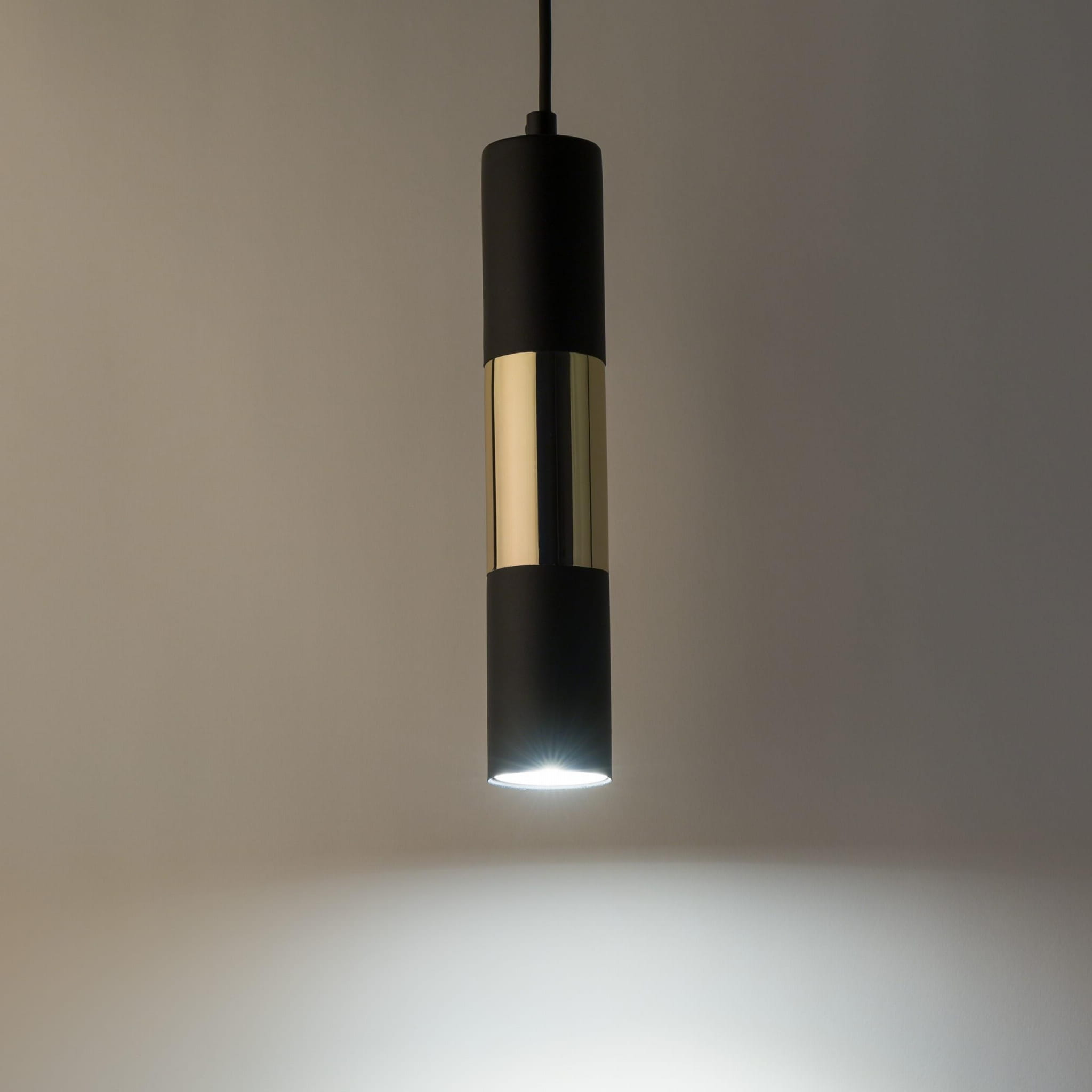 Lampa wisząca Vivien 1-punktowa w kolorze czarnym z metalowym złotym wykończeniem. Cylindryczny kształt z matowej czerni i błyszczącego złota, zawieszona na cienkim przewodzie. Emituje oświetlenie w dolnej części.