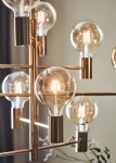 Lampa wisząca Paris mosiężna z 10 punktami świetlnymi, z przezroczystymi żarówkami w okrągłych kloszach. Kąt ujęcia zbliżony na detale, ukazujący metalową konstrukcję i eleganckie wykończenie. Tło neutralne, podkreślające design lampy.