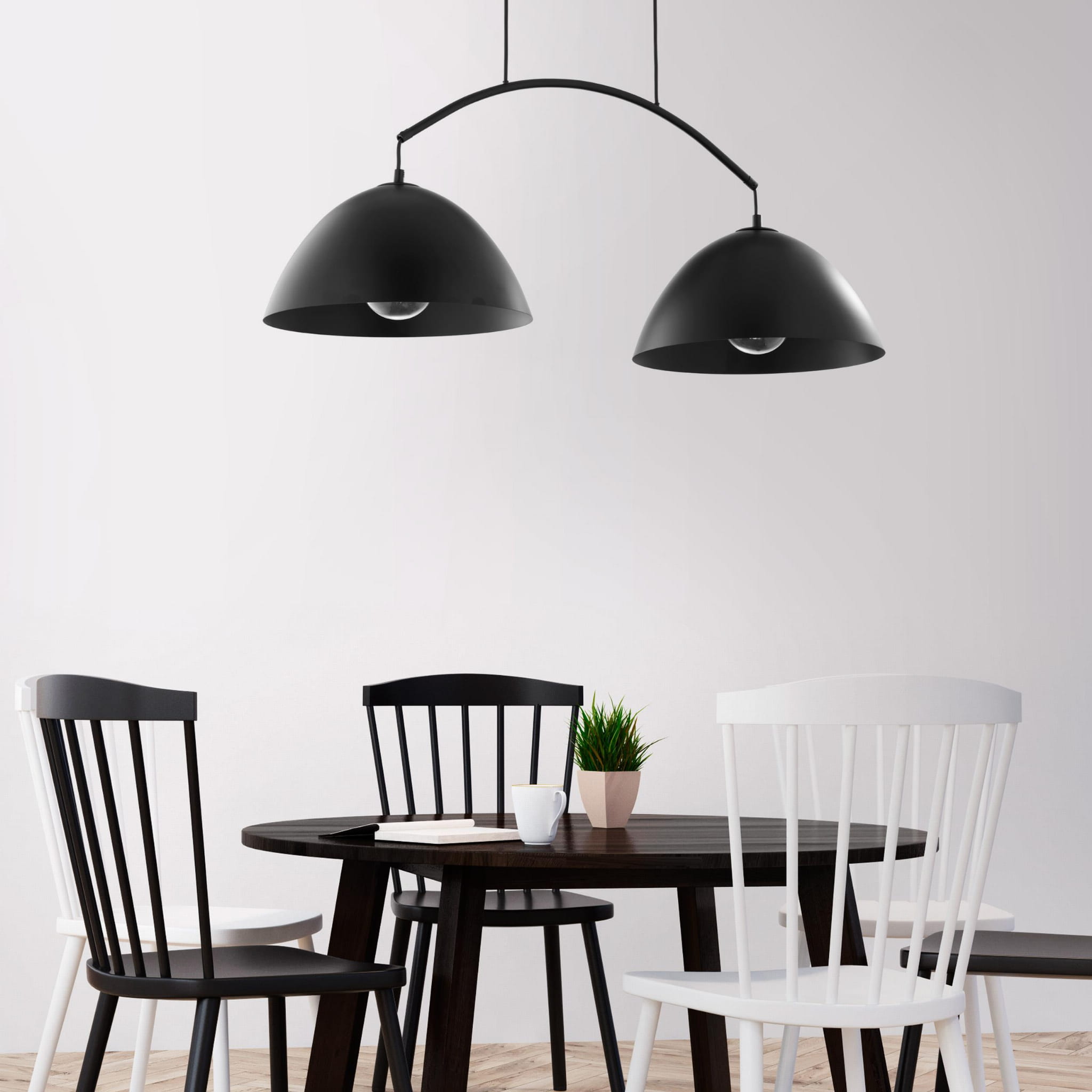 Lampa wisząca Faro 2-punktowa w kolorze czarnym z dwiema półkulistymi kloszami, zawieszona nad okrągłym stołem w jadalni. W tle białe ściany i drewniana podłoga, obok czarne i białe krzesła oraz doniczka z rośliną.