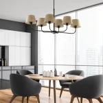 Lampa wisząca Chicago 6-punktowa w kolorze czarnym z kloszami z lnu, zawieszona nad okrągłym stołem w nowoczesnym wnętrzu. Stelaż czarny, klosze jasne. Produkt w aranżacji z szarymi krzesłami i drewnianym stołem.