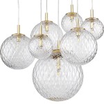 Lampa wisząca Cadix 7-punktowa z przezroczystymi, diamentowo ciętymi kulami i złotymi elementami mocującymi. Kula główna jest większa, pozostałe mniejsze, zawieszone na cienkich linkach. Przezroczyste szkło tworzy efektowne odbicia światła.