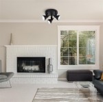 Czarna lampa sufitowa 3-punktowa Focus, zamontowana na suficie, z regulowanymi reflektorami, o nowoczesnym, minimalistycznym designie. Widoczna w jasnym wnętrzu z białym kominkiem i dużym oknem.