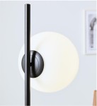 Lampa podłogowa Dione 1-punktowa w kolorze czarnym i białym. Posiada prosty, czarny stelaż oraz okrągły biały klosz. Ujęcie z boku, ukazujące detale mocowania klosza do podstawy. Tło jasne, minimalistyczne.
