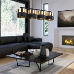 Czarna i złota lampa wisząca Hilton 4-punktowa z cylindrycznymi kloszami, zawieszona nad stolikiem kawowym w nowoczesnym wnętrzu. Widoczna sofa, kominek i okna z widokiem na zewnątrz.