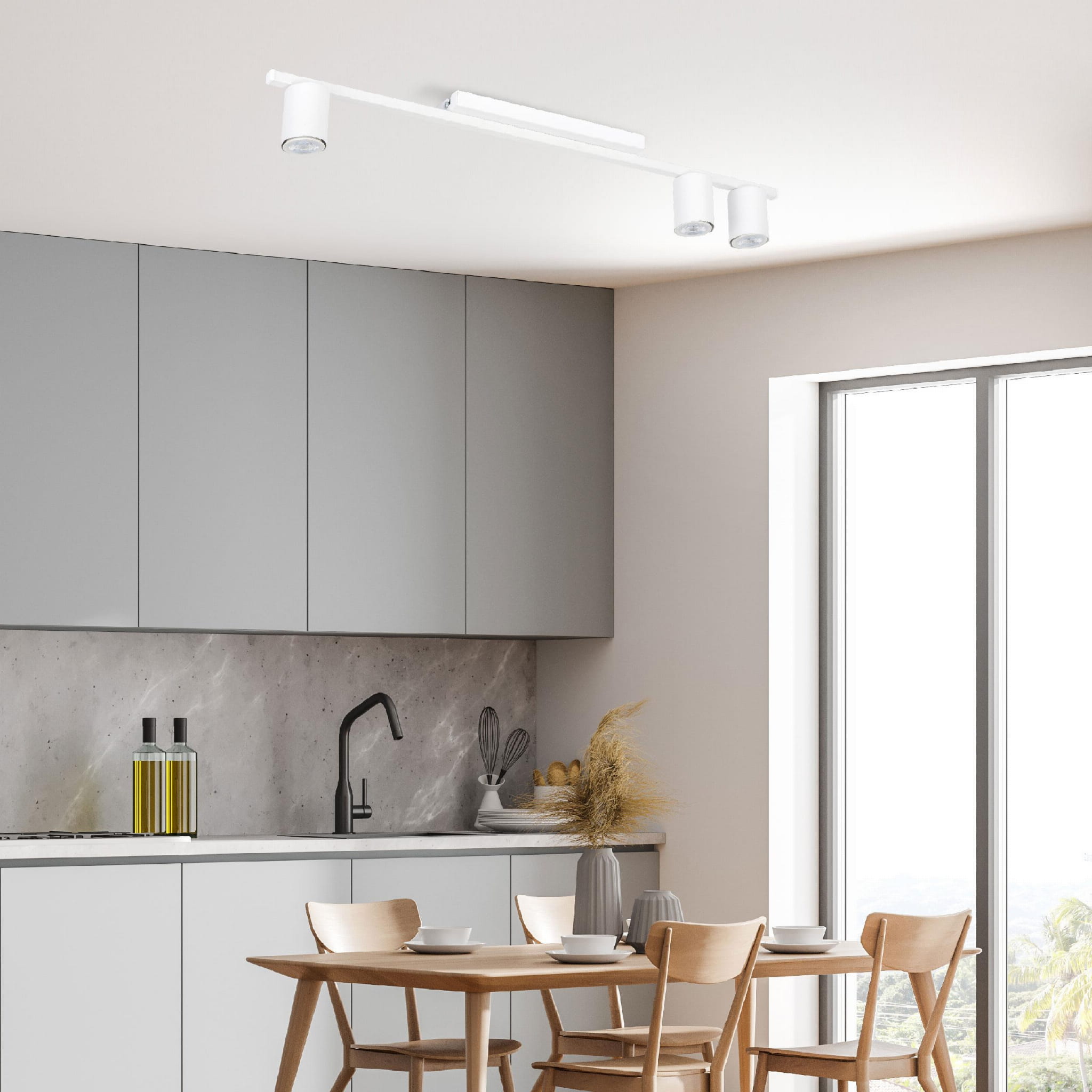 Lampa sufitowa 3-punktowa Logan White w kolorze białym, zamontowana na suficie w nowoczesnej kuchni. Trzy okrągłe źródła światła skierowane w dół, na tle szarych szafek i jasnych ścian. Stół z drewnianymi krzesłami oraz akcesoria kuchenne w tle.