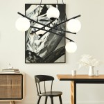 Lampa wisząca Essa 5-punktowa w kolorze czarnym z opalowymi kulami. Ułożona dynamicznie, z pięcioma źródłami światła na czarnych ramionach. W tle minimalistyczne wnętrze z drewnianym stołem, czarnym krzesłem i dekoracjami.