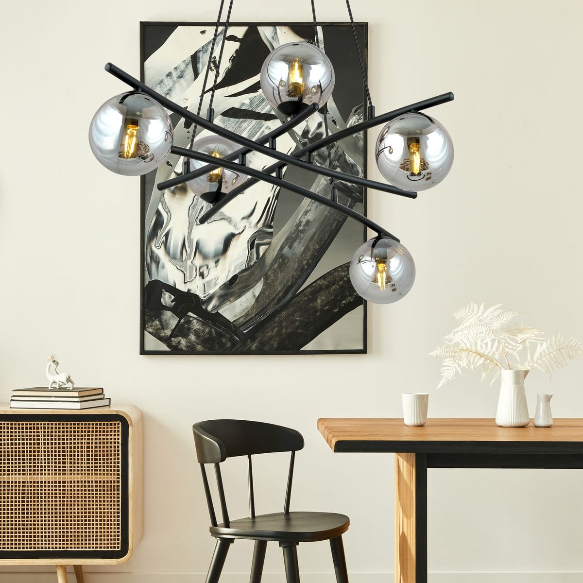 Lampa wisząca Essa 5-punktowa w kolorze czarnym i grafitowym. Posiada pięć okrągłych kloszy w metalicznym wykończeniu, zawieszona na krzyżujących się ramionach. Widoczna w nowoczesnym wnętrzu, nad drewnianym stołem i czarnym krzesłem.